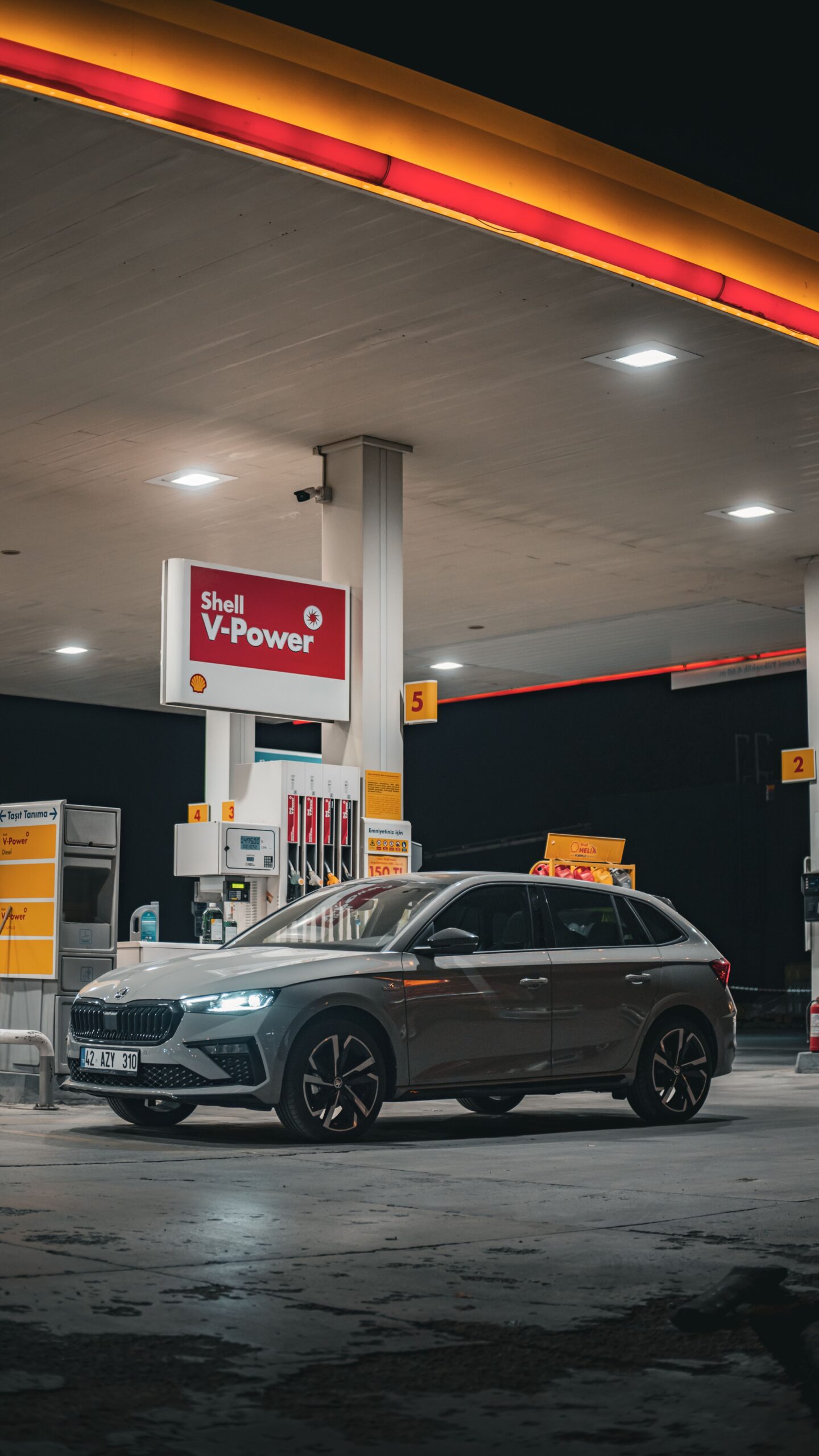 A sleek car parked at a Shell gas station during the night, modern design.