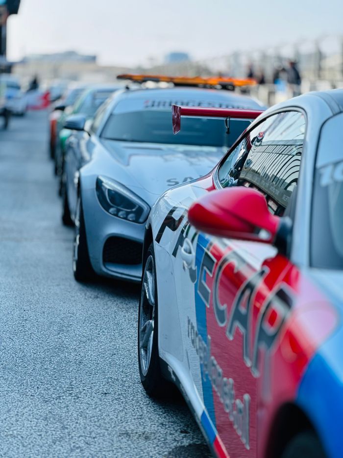 Vibrant safety cars lined up on a racing track, ready for action on a bright day.